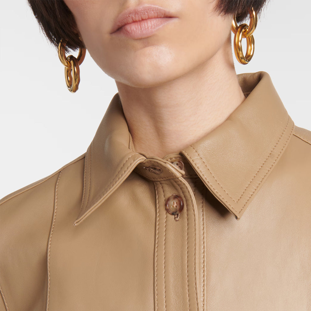 Close-up of a beige leather jacket with a person wearing it, focusing on the collar and buttons.