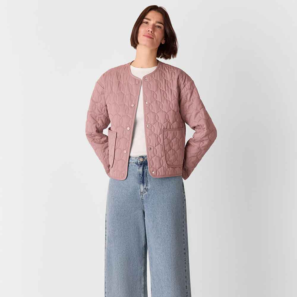 a woman wearing pink quilted pattern jacket on a light background