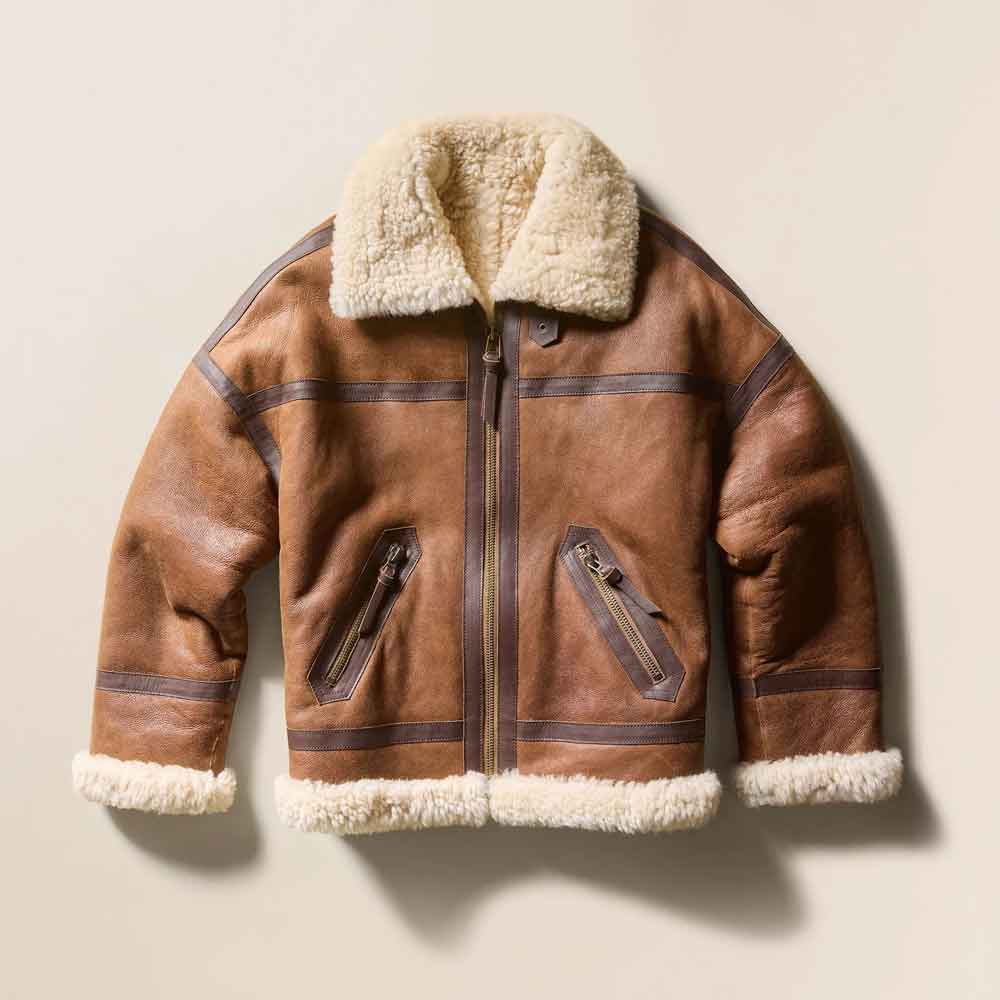 A brown leather aviator-style jacket with a thick cream faux shearling lining on the collar, cuffs, and hem, displayed against a light beige background.
