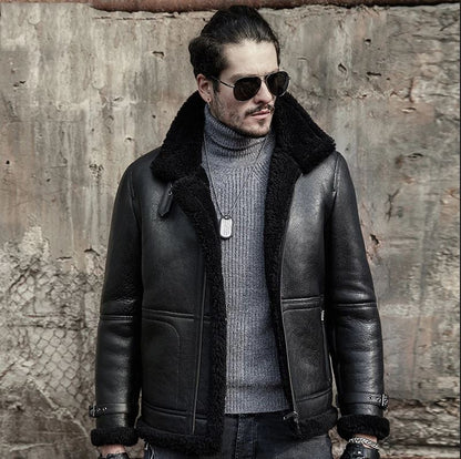 Man wearing a black leather jacket with fur collar and sunglasses against a textured wall.