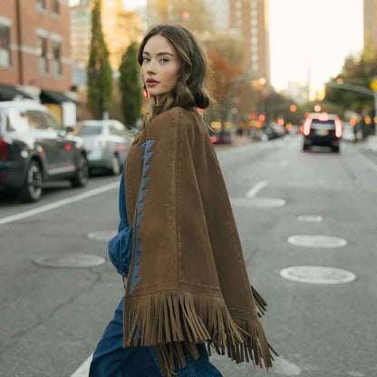 Woman wearing a brown fringed poncho on a city street