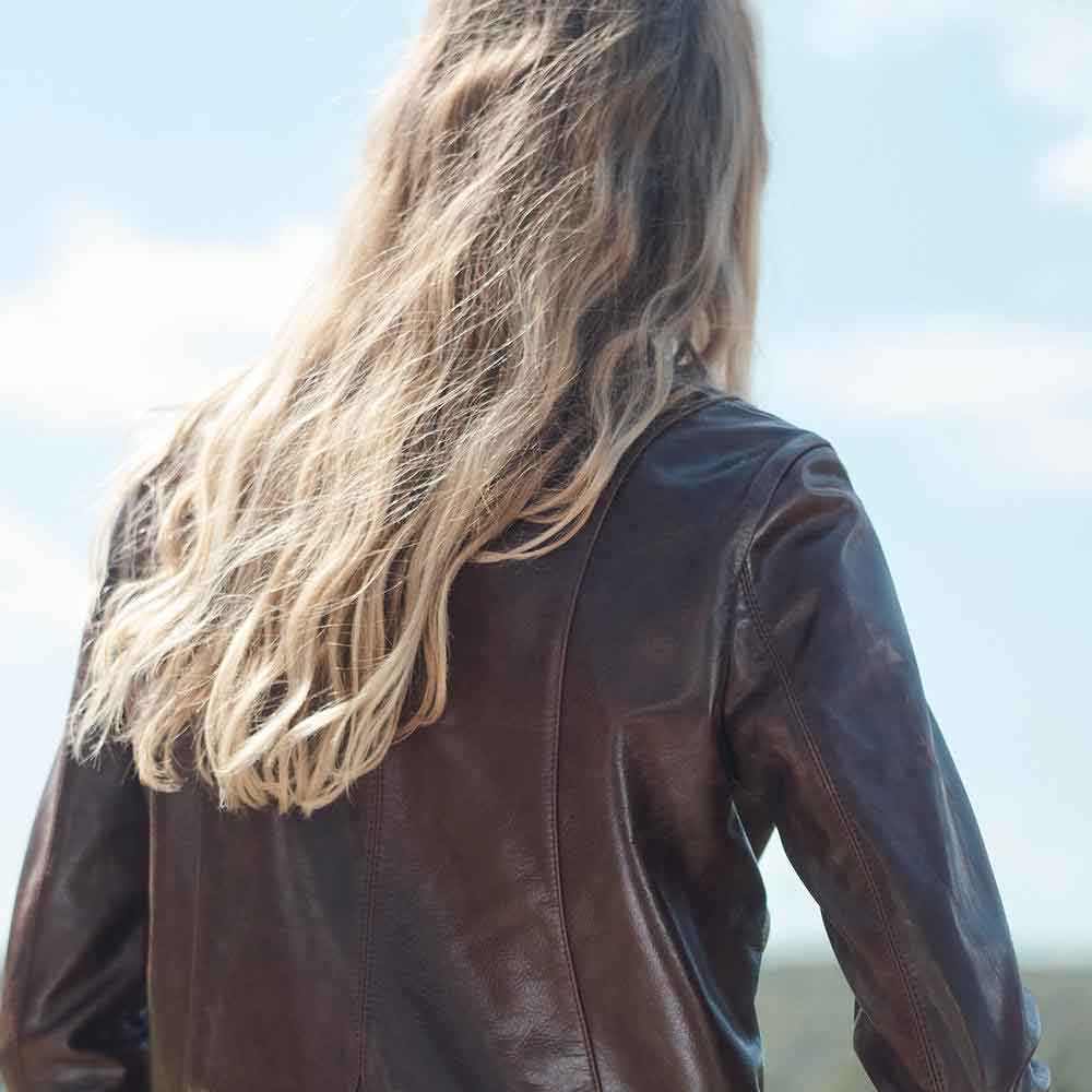 Person wearing a brown leather jacket with a blurred background