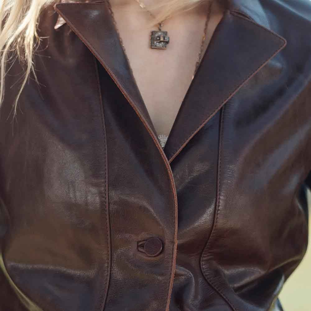 Close-up of a person wearing a brown leather jacket with a blurred background