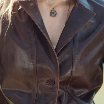 Close-up of a person wearing a brown leather jacket with a blurred background