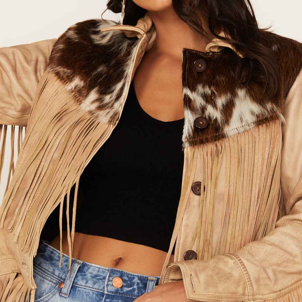 Person wearing a beige fringed jacket with cowhide pattern and black top