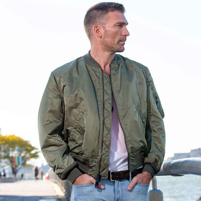 Man wearing a green bomber jacket standing outdoors with a blurred background