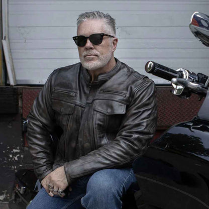 Man wearing sunglasses and a leather jacket sitting on a motorcycle.