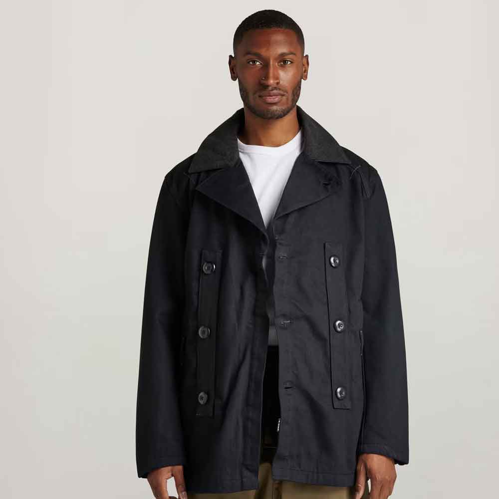 Man wearing a black coat against a plain background