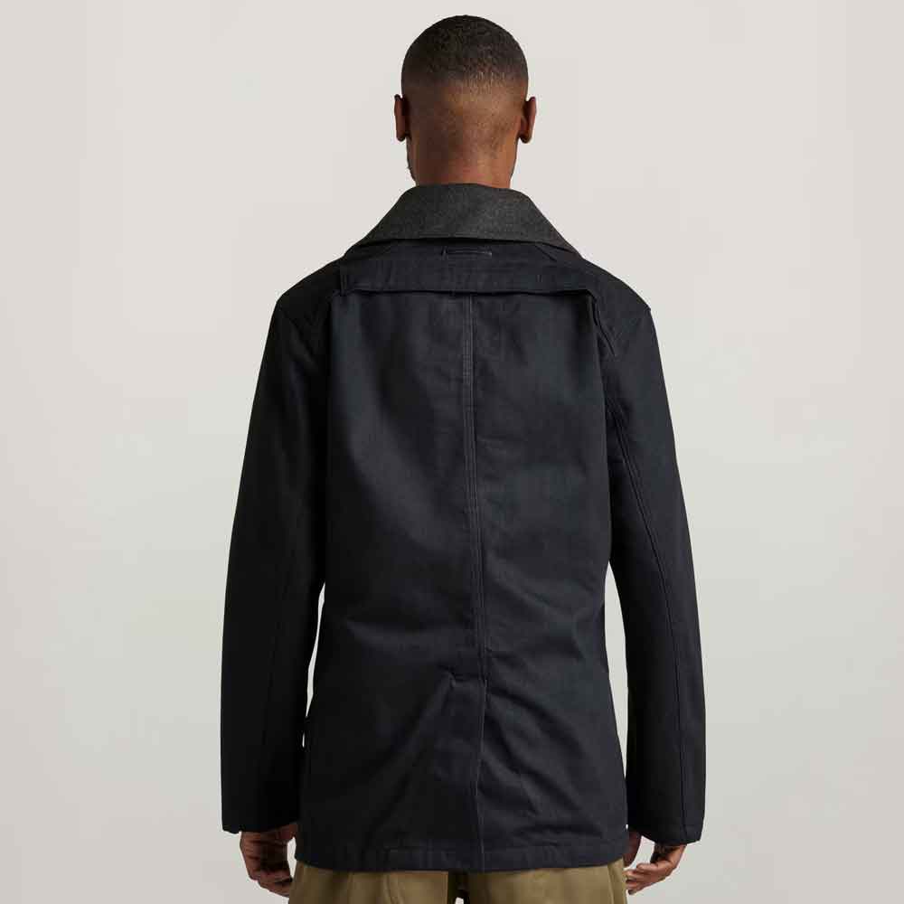 Person wearing a black coat from behind on a light gray background