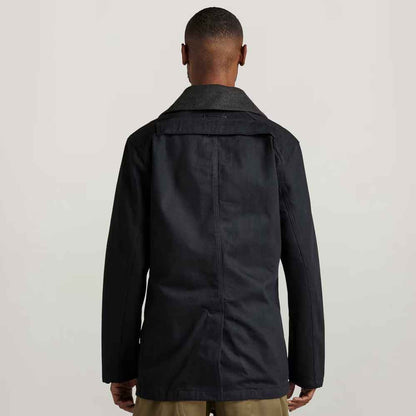 Person wearing a black coat from behind on a light gray background