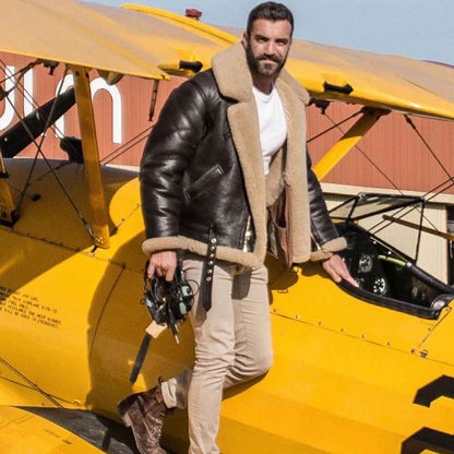 Man in a leather jacket standing next to a yellow biplane