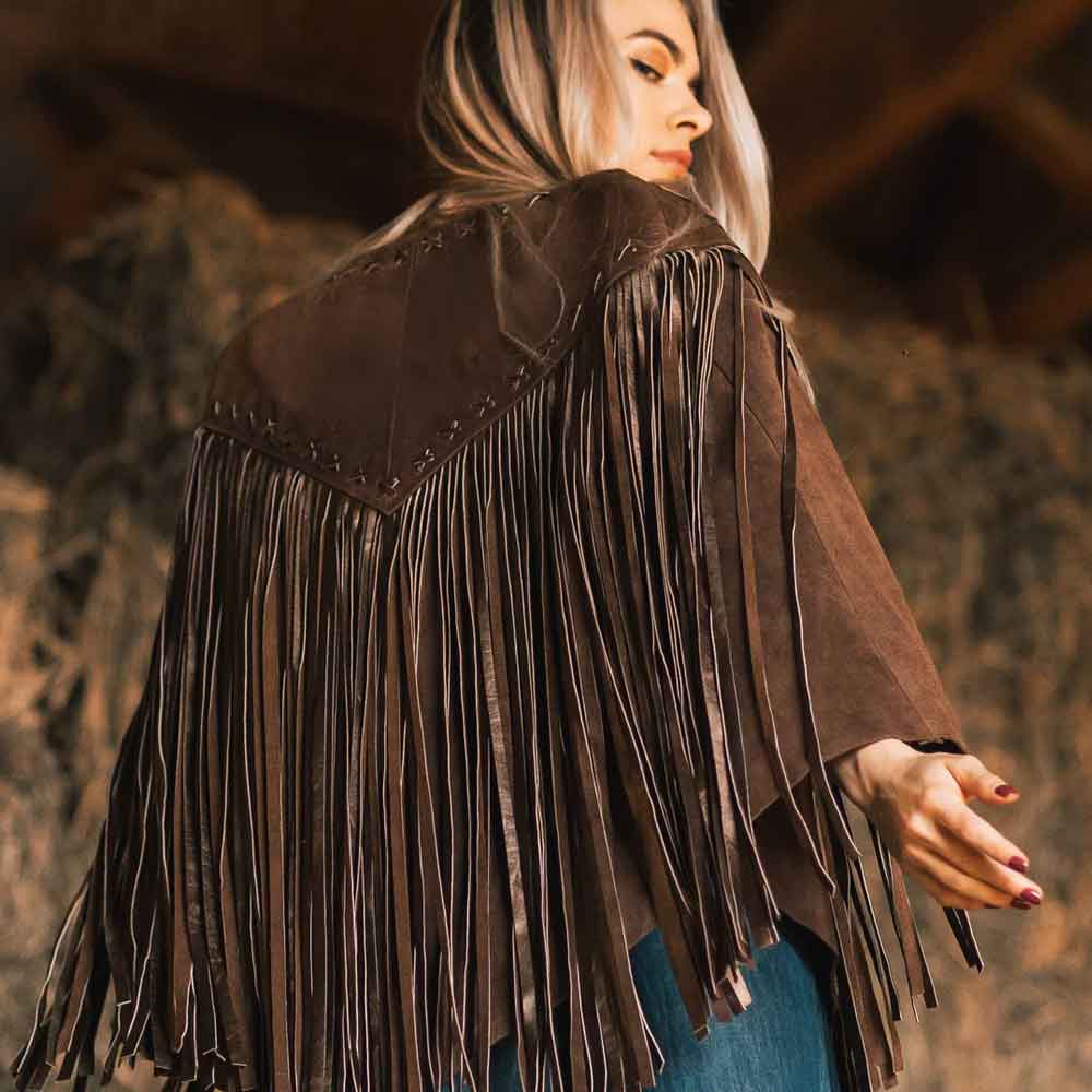 Person wearing a brown fringed jacket in a barn setting
