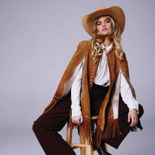 Woman in a cowboy outfit with a brown poncho and hat on a gray background