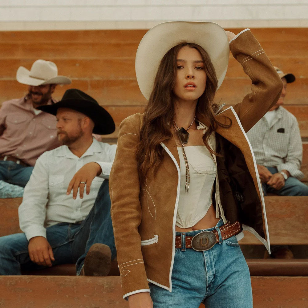 Woman in cowboy hat and jacket with people in the background