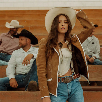 Woman in cowboy hat and jacket with people in the background