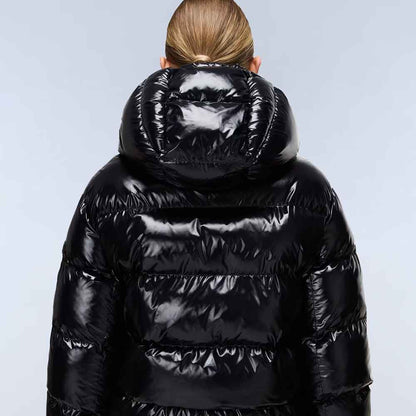 A person viewed from behind wearing a shiny black puffer jacket with a large padded hood, against a light gray studio background.