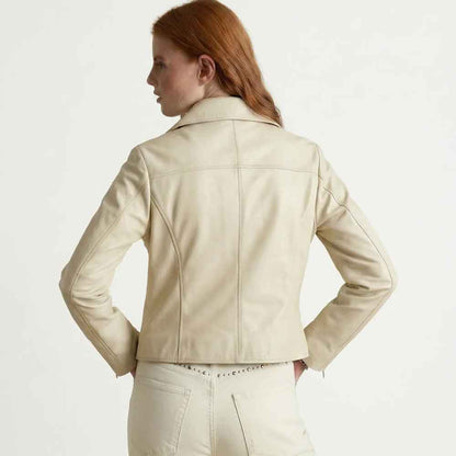 A woman with red hair is shown from the back wearing a light beige leather jacket and matching light beige pants against a plain white studio background.